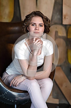 The girl in a white blouse poses in a seat in style of the seventieth years