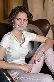 The girl in a white blouse poses in a seat in style of the seventieth years