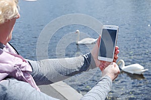 A girl in a white cap photographs the water landscape on the phone. St. Veronica& x27;s Day Photographer& x27;s Day .