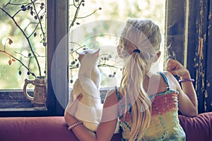 Girl with white cat looking through window