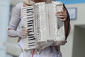 Girl in white clothes plays the white accordion