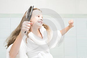 Girl in a white coat dancing in the bathroom and combing her hair