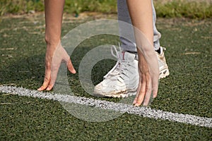 a girl in white dirty crossovers stands on the stripes on the gozon in the stadium and is going to run, running in the