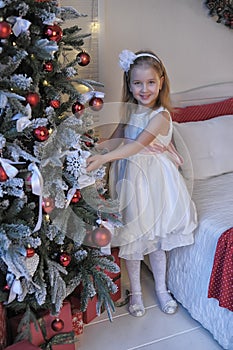Girl in white dress at the Christmas tree