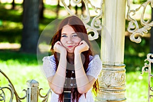 The girl in a white dress leans on a signature stamp of an acoustic guitar