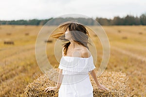 A girl in a white dress and with long hair turns her head, the hair develops on her fac