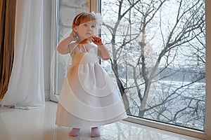Girl in white dress next to a large window