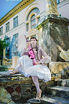 Girl in a white dress with a pink rifle plays airsoft