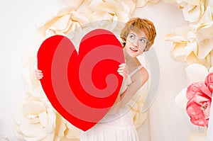 Girl in white dress with red heart in hands