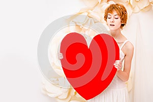 Girl in white dress with red heart in hands
