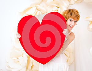 Girl in white dress with red heart in hands