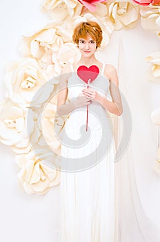 Girl in white dress with red heart in hands