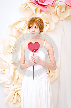 Girl in white dress with red heart in hands