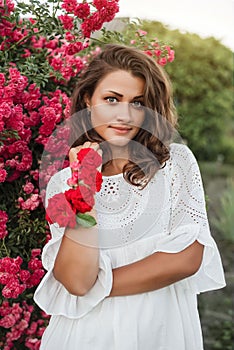 girl in a white dress with roses on her hand blows off the petals from the palm.