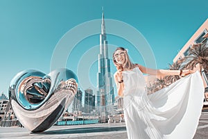 Girl in white dress on the square near Dubai Mall and the famous skyscraper Burj Khalifa