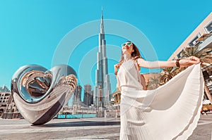 girl in white dress on the square near Dubai Mall and the famous skyscraper Burj Khalifa