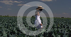 A girl in a white dress stands on a green field