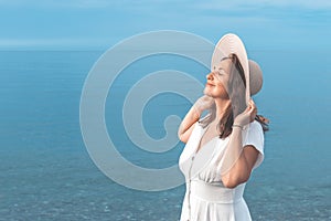 A girl in a white dress stands on the seashore