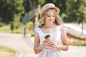 Girl in white dress and straw hat holding paper coffee cup and walking with closed eyes