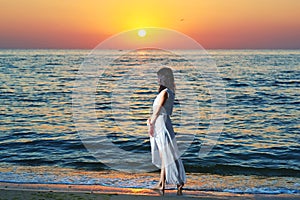 Girl in white dress on sunset`s background.