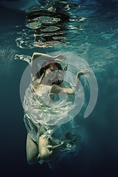 A girl in a white dress swims underwater as if flying in zero gravity