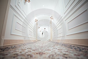 A girl in a white dress walking along a white corridor. Beautiful fashion girl walking along the corridor in a dress. Dress from