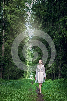 Girl in a white dress walks through a spruce forest, walk alone along a path in the forest