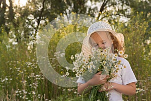 Girl in a white dress and white hat with a bouquet of daisies