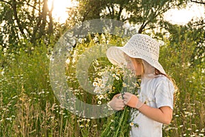 Girl in a white dress and white hat with a bouquet of daisies