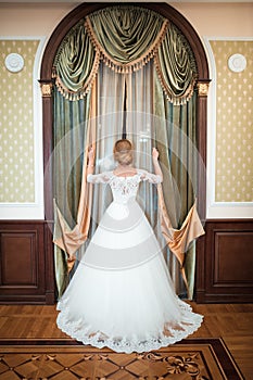 Girl in a white dress by the window. tender princess in a long light white dress with bare shoulders, a fabulous girl, a vintage