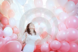 Girl in white flies among pink balloons