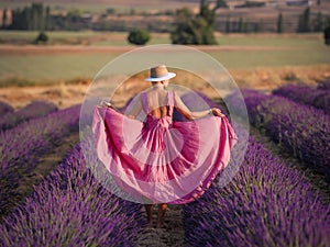 A girl in a white flying dress stands in a lavender field enjoying the aroma of flowers