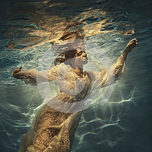 A girl in a white lace dress swims underwater as if flying in zero gravity