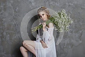 Girl white light dress and curly hair, portrait of woman with flowers at home near the window, purity and innocence. Curly blonde