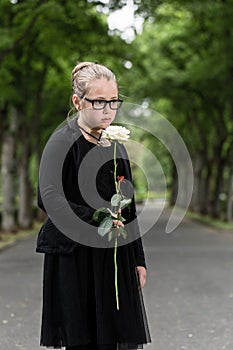 Girl with white rose mourning deceased on graveyard