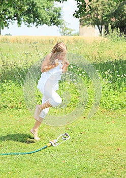 Girl in white running thru sprinkler