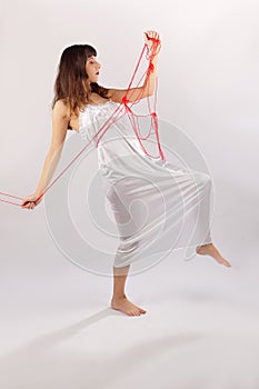 Girl white silk nightie struggling with red thread on white background