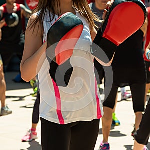 Girl in White Sportswear doing Fitness with Punching Mitts in Outdoor Class at Gym