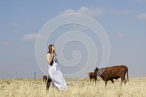 Girl in white standing next to cattle