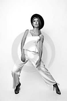 Girl in a white suit and black hat in the studio on a white background. Black and white photo