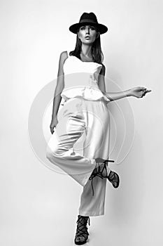 Girl in a white suit and black hat in the studio on a white background. Black and white photo
