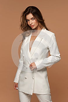 Girl in white suit posing on beige background