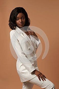 Girl in white suit posing on beige background