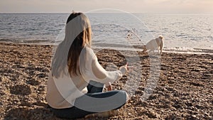 Girl in a white sweater throws up the stones and play with her siba inu cute male pet on the ocean coast slow motion