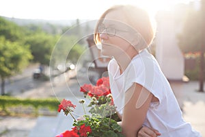 a girl in a white T-shirt and glasses stands on the balcony and enjoys beauty and care