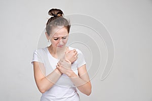 Girl in a white T-shirt massages a brush. Concept of joint pain.