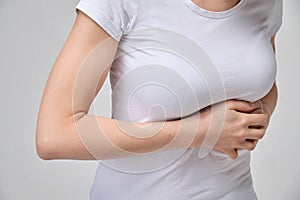 A girl in a white T-shirt is massaging under her breasts. The concept of intercostal neuralgia