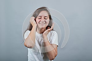 Girl in white t-shirt smiles and feel embarrased therefore close her eyes.