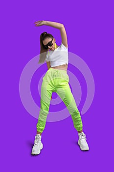 Girl in a white T-shirt and yellow neon sweatpants on a colored background