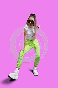 Girl in a white T-shirt and yellow neon sweatpants on a pink background